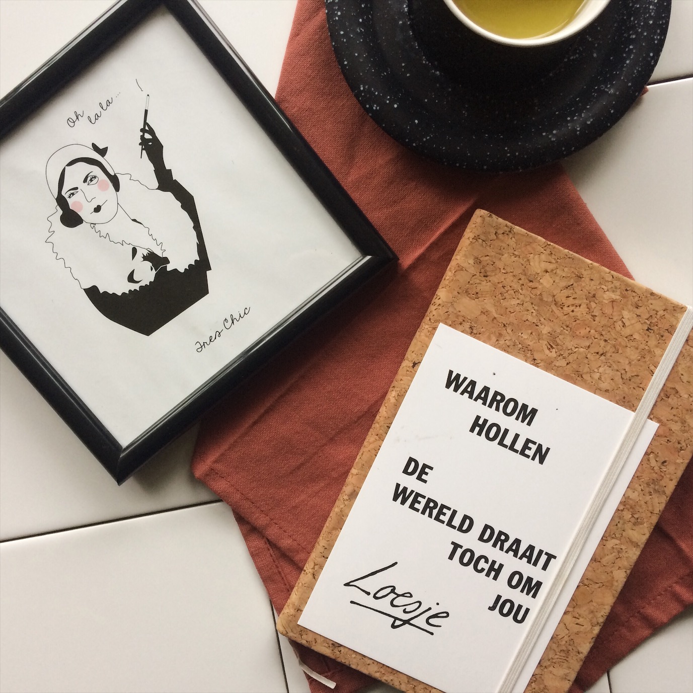 Ingezoomde Flatlay van notitieboek, loesje kaart, theekopje en schilderijtje